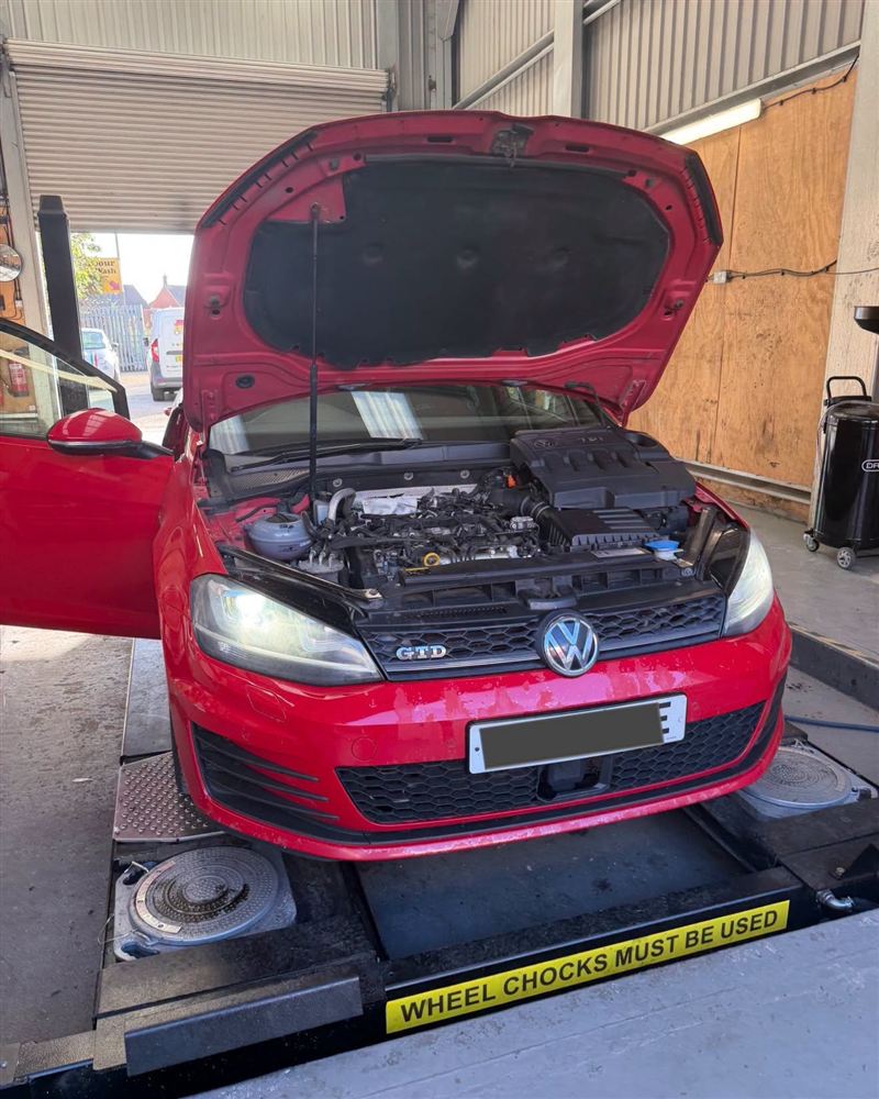 Red VW Golf with the bonnet up in the workshop